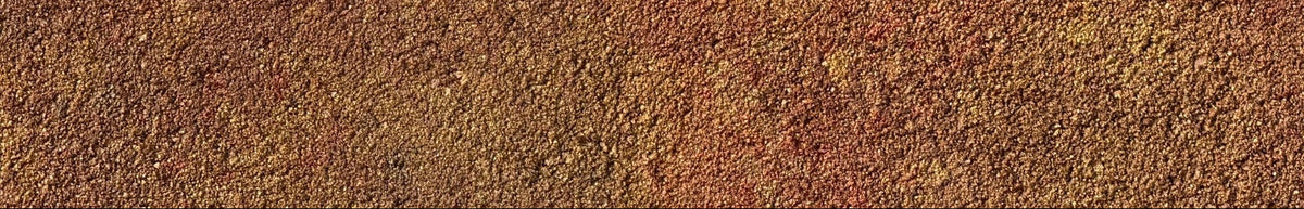 A close-up of a textured, granular surface with a mottled blend of warm earthy tones, primarily rust red, terracotta, and golden brown.